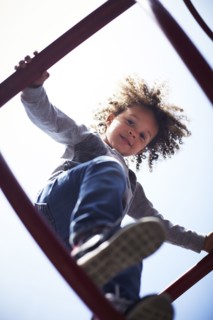 Low angle view of mixed race boy climbing on play structure