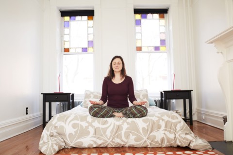 Mixed race woman meditating in bedroom