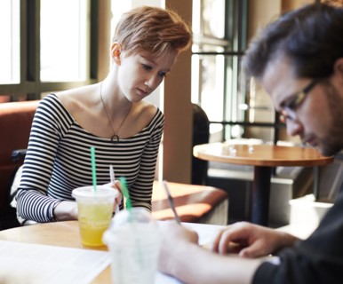 Caucasian couple writing at table in cafe