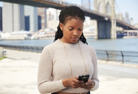 Black woman using cell phone at waterfront