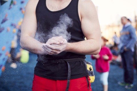 Caucasian man chalking hands at outdoor climbing wall