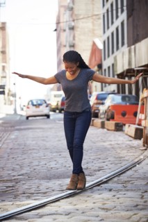 Black woman balancing on track in cobblestone city street