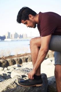 Middle Eastern man tying shoelace at waterfront