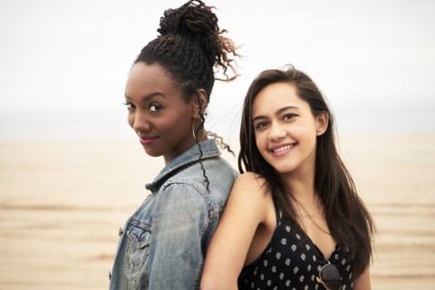 Smiling women back to back on beach
