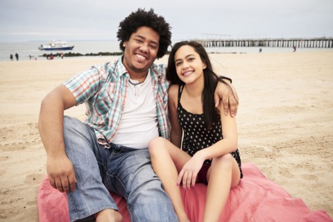 Smiling couple sitting on blanket at beach