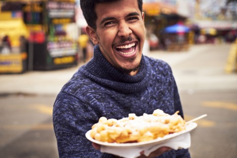 Laughing man showing plate of food at amusement park