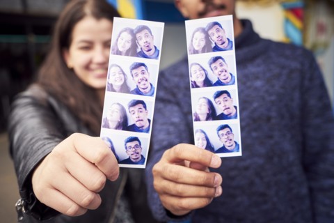 Couple showing photograph strips from photo booth