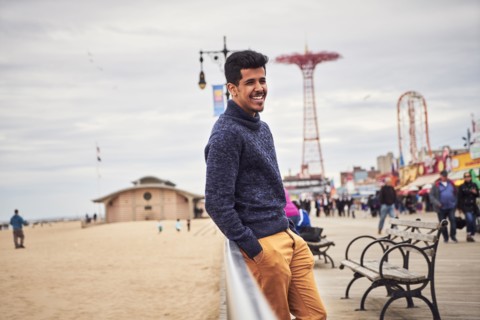 Man leaning on boardwalk railing at beach