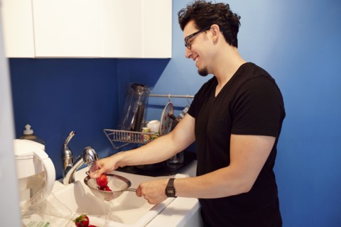 Hispanic man washing strawberries in sink