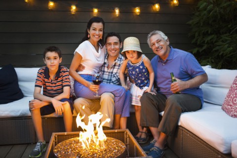 Family smiling around fire pit outdoors