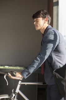 Korean businessman wheeling bicycle in office