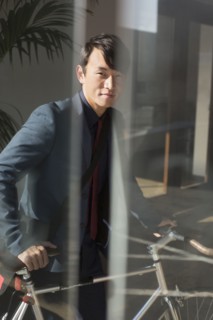Korean businessman wheeling bicycle in office