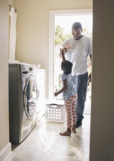 African American father and daughter doing laundry