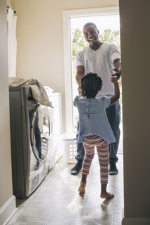 African American father and daughter doing laundry
