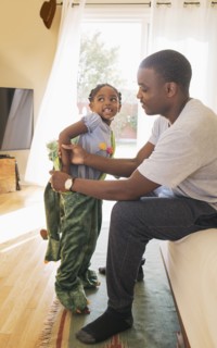 African American father helping daughter put on costume