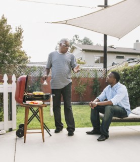 African American father and son talking at barbecue