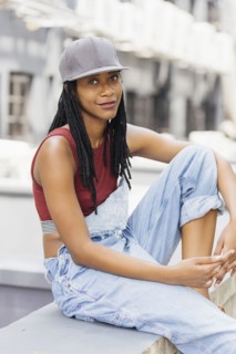 Smiling Mixed Race woman sitting on wall