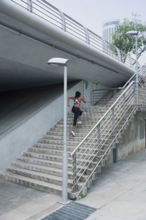 Mixed Race woman running up urban staircase