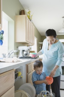 Mother and young son putting dishes in dishwasher