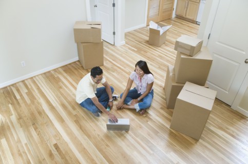 Asian couple looking at laptop in new house