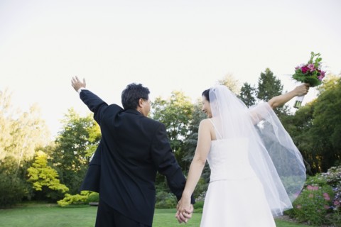 Asian newlyweds with arms raised