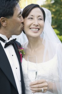 Asian groom kissing bride's cheek
