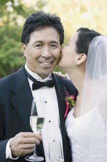 Asian bride kissing groom's cheek