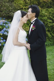 Asian groom kissing bride's forehead