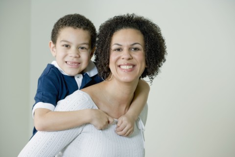 Mixed race mother giving son piggyback ride