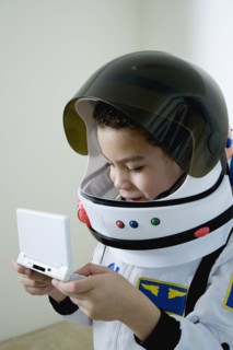 Mixed race boy in astronaut costume with video game
