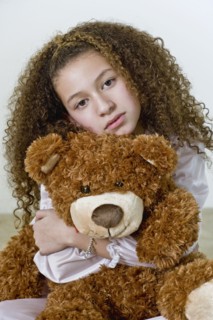Mixed race girl in nightgown with teddy bear