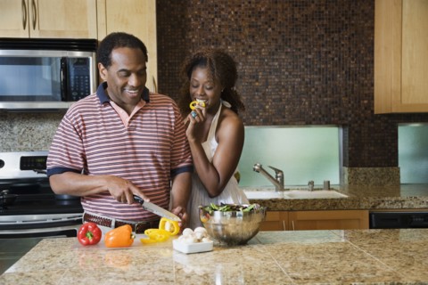 African couple fixing healthy meal in modern kitchen