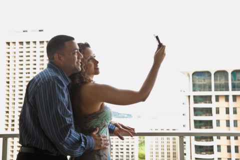 Couple taking self-portrait on urban balcony