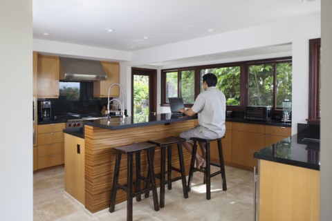 Japanese man using laptop at kitchen counter