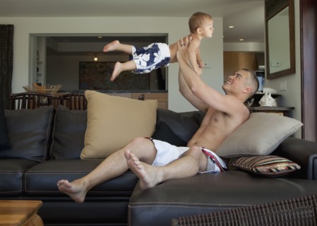 Father lifting son in living room