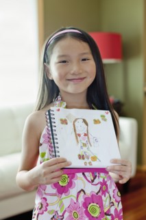 Mixed race girl holding up self-portrait drawing