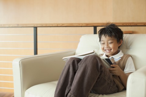 Mixed race boy reading book in armchair