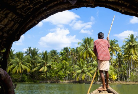 Man standing in boat on tranquil forest river