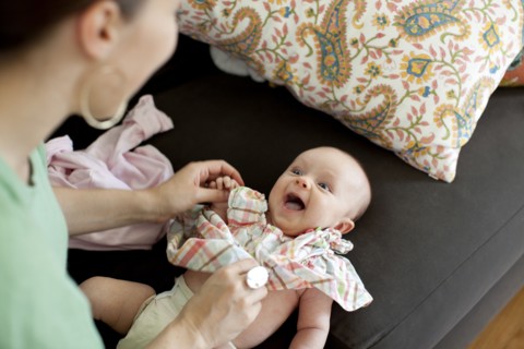 Caucasian mother changing baby daughter's clothes