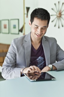 Smiling mixed race man in jacket using digital tablet