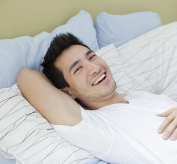 Smiling mixed race man laying in bed