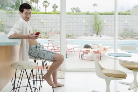 Mixed race man text messaging on cell phone