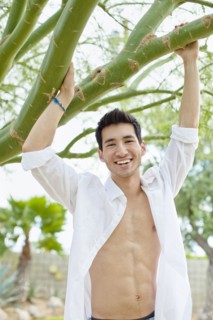 Mixed race man holding onto tree branch