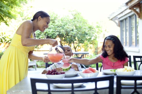 African American woman serving juice to daughter