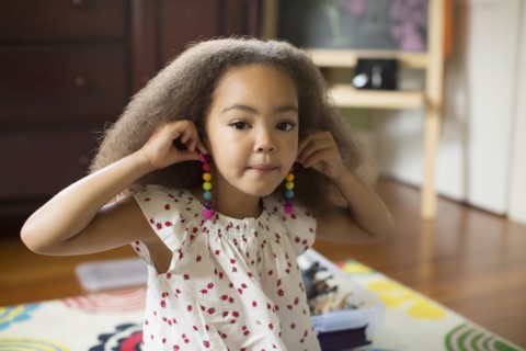 Mixed race girl trying on earrings