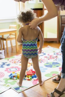 Mother putting bathing suit on daughter