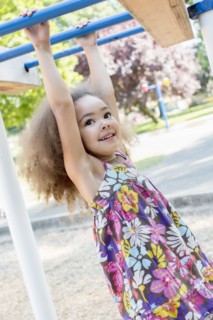 Mixed race girl hanging from bar
