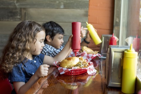Mixed race children having burgers in restaurant