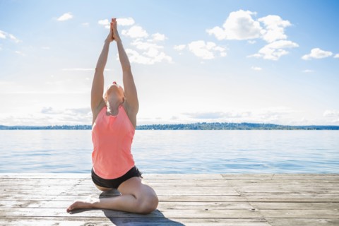 Caucasian woman practicing yoga on wooden dock