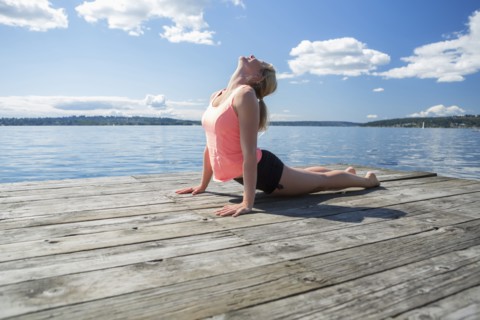Caucasian woman practicing yoga on wooden dock